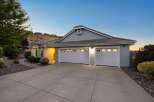 This stunning single-story home features a welcoming facade with a spacious driveway leading to a large, attached three-car garage.