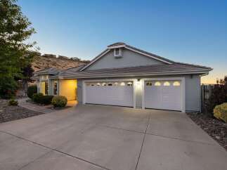 This stunning single-story home features a welcoming facade with a spacious driveway leading to a large, attached three-car garage.