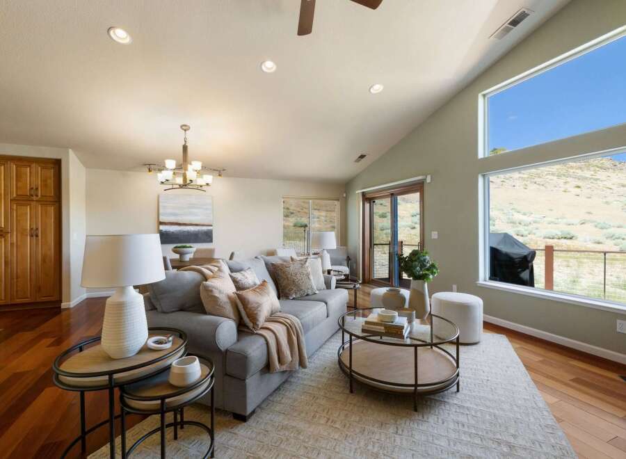 Experience breathtaking views from this stunning living room, featuring a vaulted ceiling and expansive windows that showcase the natural landscape.