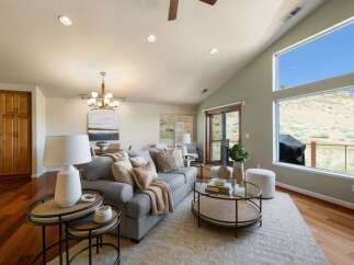 Experience breathtaking views from this stunning living room, featuring a vaulted ceiling and expansive windows that showcase the natural landscape.