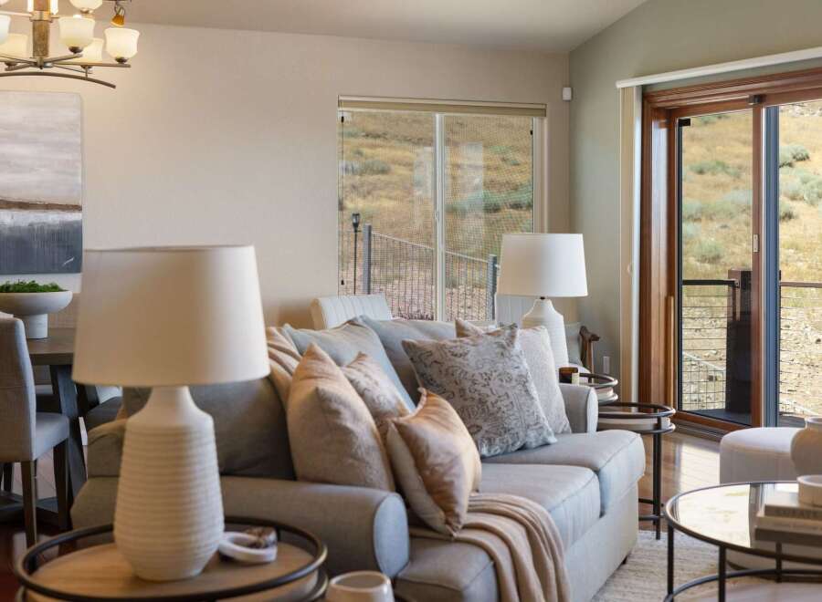 Experience comfortable living in this inviting living room, featuring a plush sofa adorned with decorative pillows and a cozy throw blanket.