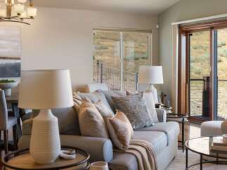 Experience comfortable living in this inviting living room, featuring a plush sofa adorned with decorative pillows and a cozy throw blanket.