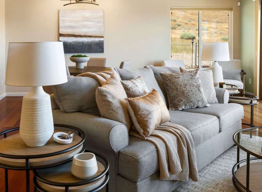 Experience comfortable living in this beautifully appointed living room, featuring a plush grey sectional sofa adorned with decorative pillows and a cozy throw.