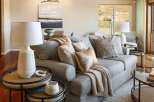 Experience comfortable living in this beautifully appointed living room, featuring a plush grey sectional sofa adorned with decorative pillows and a cozy throw.