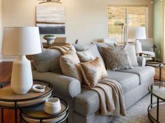 Experience comfortable living in this beautifully appointed living room, featuring a plush grey sectional sofa adorned with decorative pillows and a cozy throw.
