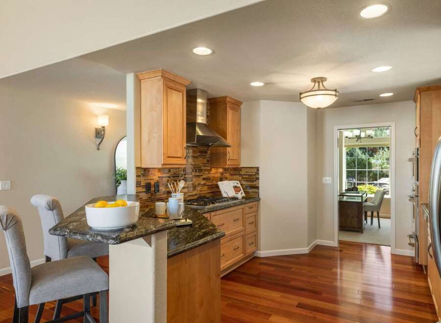 This beautifully remodeled kitchen features warm wood cabinetry, a sleek stainless steel range hood, and a stunning glass tile backsplash.
