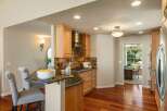 This beautifully remodeled kitchen features warm wood cabinetry, a sleek stainless steel range hood, and a stunning glass tile backsplash.