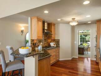 This beautifully remodeled kitchen features warm wood cabinetry, a sleek stainless steel range hood, and a stunning glass tile backsplash.