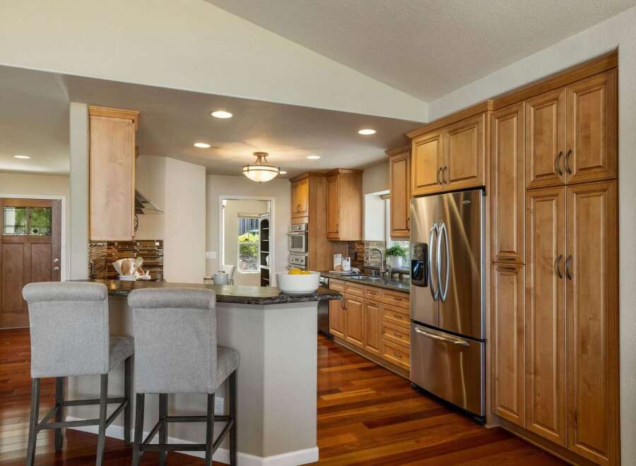 This spacious kitchen boasts beautiful natural wood cabinetry and a large stainless steel refrigerator, perfect for any home chef.