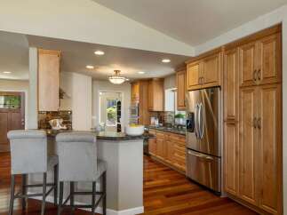 This spacious kitchen boasts beautiful natural wood cabinetry and a large stainless steel refrigerator, perfect for any home chef.
