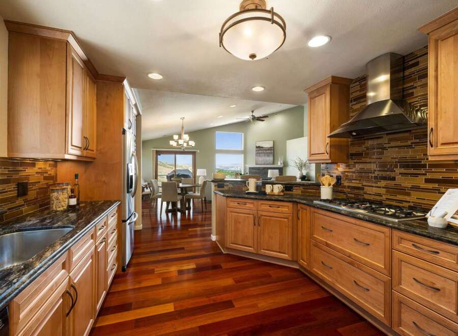 Experience luxury living in this stunning kitchen featuring custom wood cabinetry and a sleek glass tile backsplash.