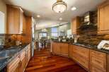 Experience luxury living in this stunning kitchen featuring custom wood cabinetry and a sleek glass tile backsplash.