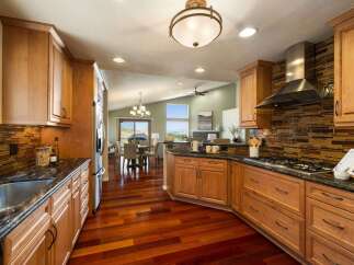 Experience luxury living in this stunning kitchen featuring custom wood cabinetry and a sleek glass tile backsplash.