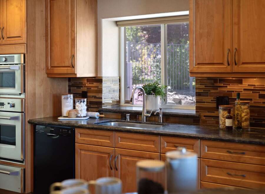 This stunning kitchen features warm cherry wood cabinetry and sleek stainless steel appliances, including a double oven and a modern dishwasher.