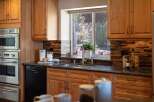 This stunning kitchen features warm cherry wood cabinetry and sleek stainless steel appliances, including a double oven and a modern dishwasher.