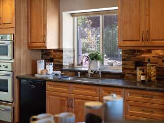 This stunning kitchen features warm cherry wood cabinetry and sleek stainless steel appliances, including a double oven and a modern dishwasher.