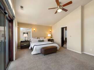 Experience ultimate comfort in this spacious master bedroom, featuring a vaulted ceiling and a modern ceiling fan for optimal air circulation.