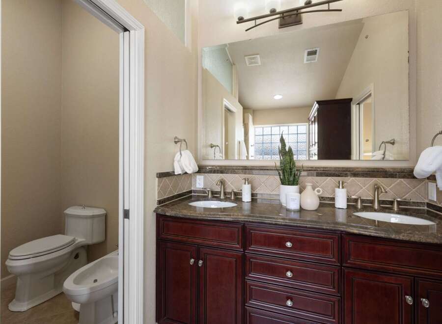 This luxurious bathroom features a spacious double vanity with a granite countertop and rich cherry wood cabinetry, perfect for ample storage.
