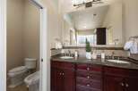This luxurious bathroom features a spacious double vanity with a granite countertop and rich cherry wood cabinetry, perfect for ample storage.