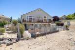 Enjoy outdoor living with this spacious deck overlooking a fenced backyard featuring raised garden beds and a greenhouse.