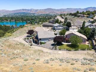 Experience breathtaking panoramic views from this stunning hillside estate, overlooking a serene lake and majestic mountains.