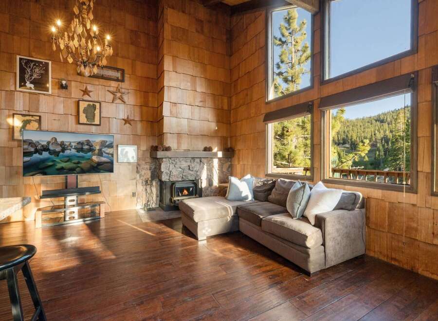 Experience rustic charm in this stunning living room, featuring a grand stone fireplace and a beautiful wood-paneled accent wall.