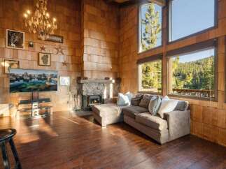 Experience rustic charm in this stunning living room, featuring a grand stone fireplace and a beautiful wood-paneled accent wall.