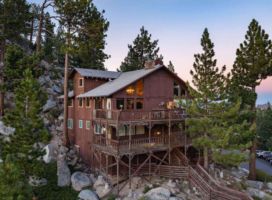 Nestled amidst towering pine trees and natural rock formations, this multi-level wooden home offers breathtaking views and ample outdoor living space.