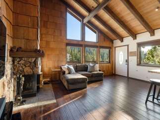Experience rustic charm in this mountain retreat featuring a stunning stone fireplace and soaring vaulted ceilings with exposed wooden beams.