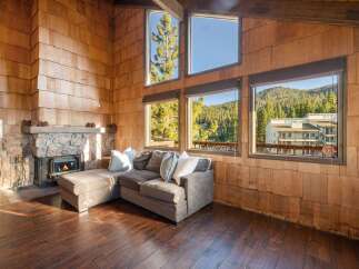 Experience rustic charm in this cozy living room featuring a stone fireplace and a plush sectional sofa perfect for relaxing.