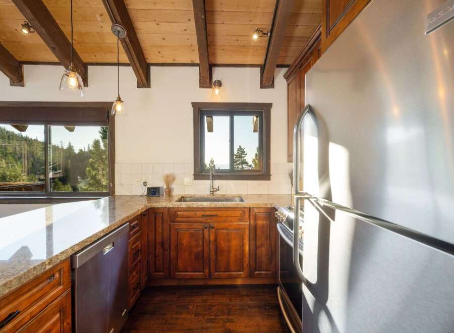 Experience rustic charm in this kitchen featuring warm wooden cabinetry and exposed beams, complemented by granite countertops.