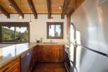 Experience rustic charm in this kitchen featuring warm wooden cabinetry and exposed beams, complemented by granite countertops.