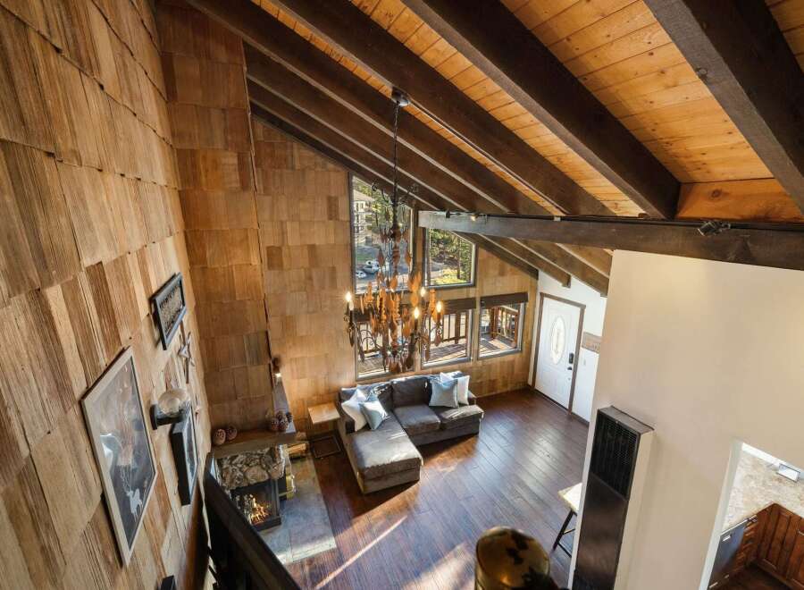 Experience rustic charm in this stunning mountain retreat, featuring a grand living area with a soaring wood-beamed ceiling and a striking stone fireplace.
