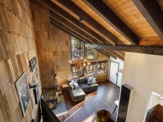 Experience rustic charm in this stunning mountain retreat, featuring a grand living area with a soaring wood-beamed ceiling and a striking stone fireplace.