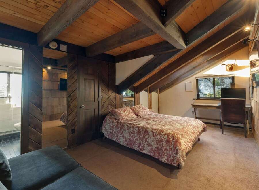 Experience rustic charm in this unique attic bedroom, featuring exposed wooden beams and a cozy bed with a nature-inspired duvet.