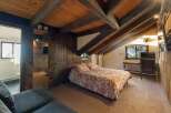 Experience rustic charm in this unique attic bedroom, featuring exposed wooden beams and a cozy bed with a nature-inspired duvet.