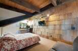 This charming bedroom features a rustic wood-shingled accent wall, creating a warm and inviting atmosphere.