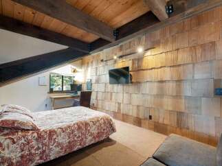 This charming bedroom features a rustic wood-shingled accent wall, creating a warm and inviting atmosphere.