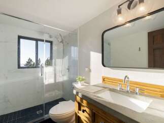 Experience modern luxury in this stunning bathroom, featuring a sleek glass-enclosed shower with marble tile and a convenient toilet.