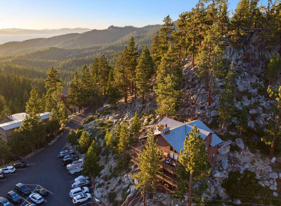 Nestled amidst towering pine trees and rocky terrain, this stunning property offers breathtaking panoramic views of a serene lake and rolling hills.