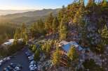 Nestled amidst towering pine trees and rocky terrain, this stunning property offers breathtaking panoramic views of a serene lake and rolling hills.