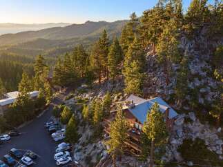 Nestled amidst towering pine trees and rocky terrain, this stunning property offers breathtaking panoramic views of a serene lake and rolling hills.