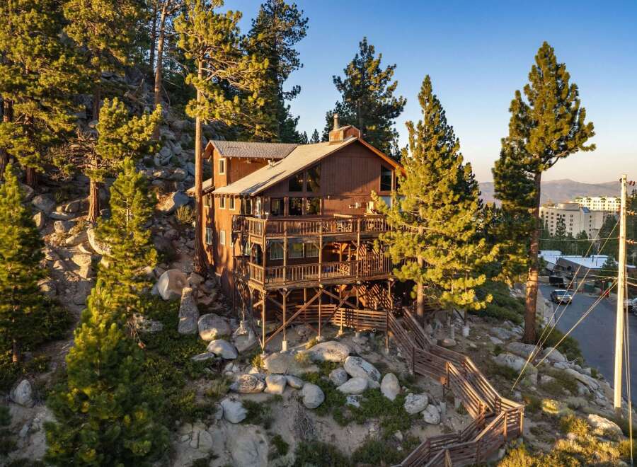 Experience breathtaking mountain views from this stunning wooden lodge, nestled amidst towering pine trees and rocky terrain.