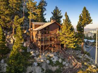 Experience breathtaking mountain views from this stunning wooden lodge, nestled amidst towering pine trees and rocky terrain.