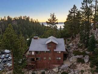 Nestled amidst a serene forest landscape, this charming rustic home offers breathtaking lake views at sunset.