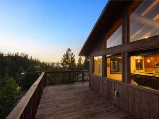 Experience breathtaking sunset views from this stunning mountain home, featuring a spacious wooden deck perfect for outdoor entertaining.