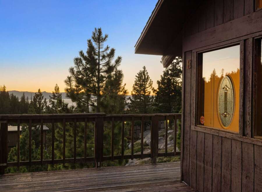 Experience breathtaking sunset views from this charming cabin deck, overlooking a serene lake and majestic mountains.
