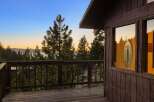 Experience breathtaking sunset views from this charming cabin deck, overlooking a serene lake and majestic mountains.