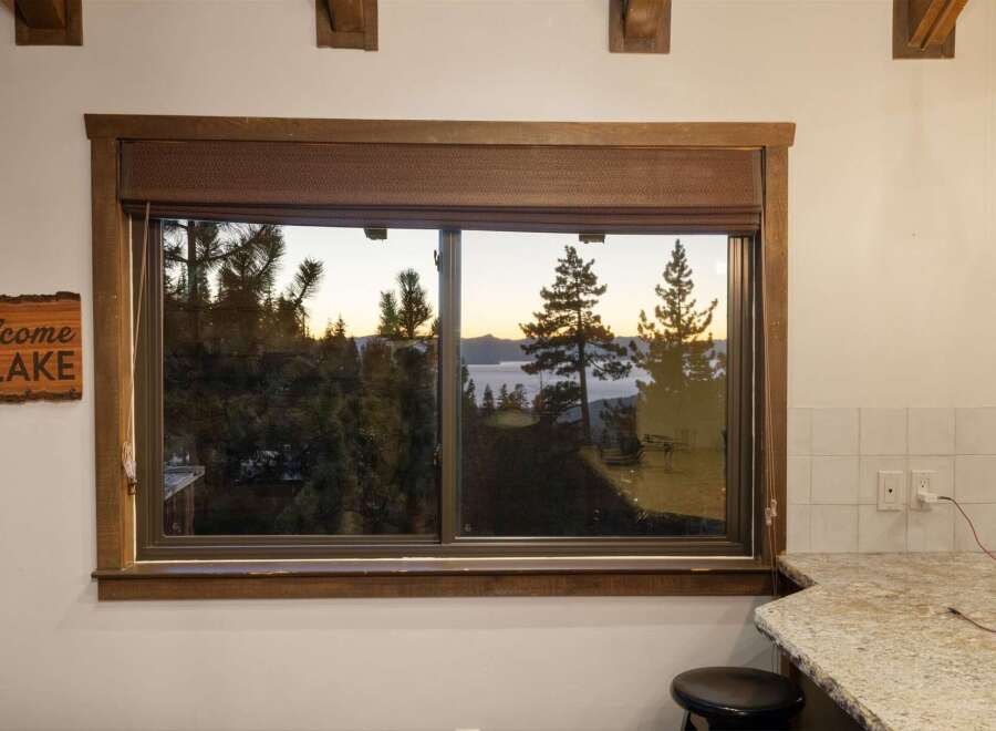 Enjoy breathtaking lake views from this stunning property, framed by a rustic wooden window.