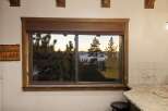 Enjoy breathtaking lake views from this stunning property, framed by a rustic wooden window.